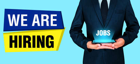 We are Hiring Banner with Person Holding Mobile and Job Text backdrop. Modern hiring concept backgroundの写真素材