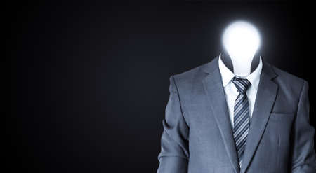 Businessman with light bulb head on dark background. Idea and solution conceptの写真素材