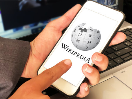 29.1, Pakistan. Wikipedia editorial background man touching the mobile screen and laptop in the backdropのeditorial素材