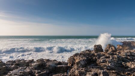 Waves of the Atlantic ocean beating against the stone shore on a clear Sunny day, Portugalの写真素材