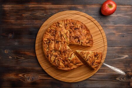 Cornish apple pie with a cut piece on the shoulder blade top view on rustic style brown background....