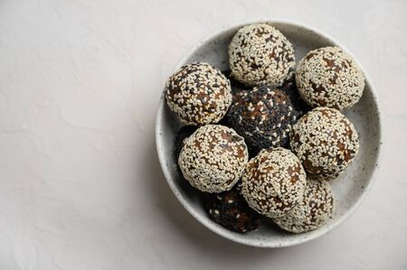 Homemade healthy energy balls made from fruits, nuts, cocoa, honey in a light vase on a white background. Copy space. Top viewの写真素材