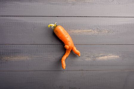 Ugly carrot concept on wooden background. Copy spaceの写真素材