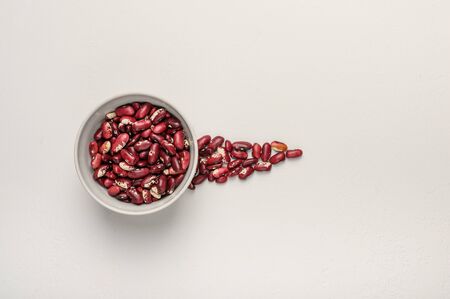 Bowl with red beans on a light textured background. Next to the grain is poured in the form of an arrowの写真素材