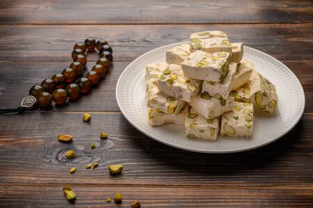Eastern Arabic nougat sweetness with pistachios on a ceramic plate on a light background. Close upの写真素材