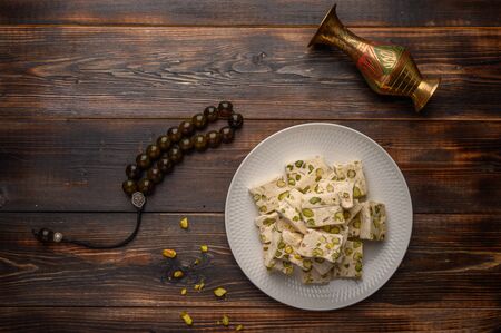 Eastern Arabic nougat sweetness with pistachios on a ceramic plate on a light background. Close up