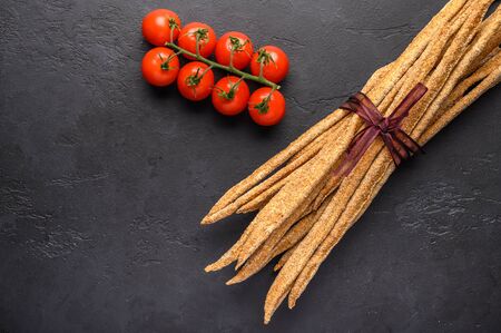 Italian traditional rye bread grissini and cherry on dark background. Close up. Copy space