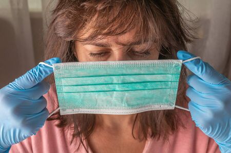 Woman in medical gloves wearing medical face mask to protect herself from pollution, germs and...