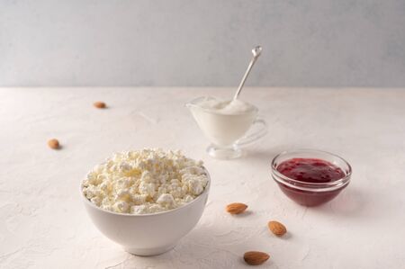 Cottage cheese in a bowl. sour cream and fruit jam on a light background