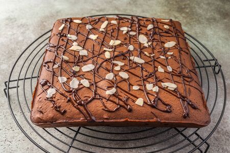 Homemade brownie with chocolate and almond petals on a metal stand. Close upの写真素材