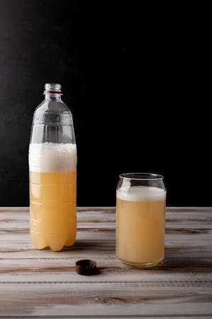Misted plastic bottle of beer or light rye kvass with glass cup with foam. Selective focus....