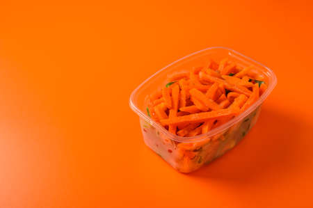 Frozen vegetables carrot in a plastic tray on an orange background, selective focus, concept diets and healthy eating with copy space close upの写真素材