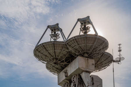 Large paraboloic antennas to transmit signals into space to satellites against the blue sky with...
