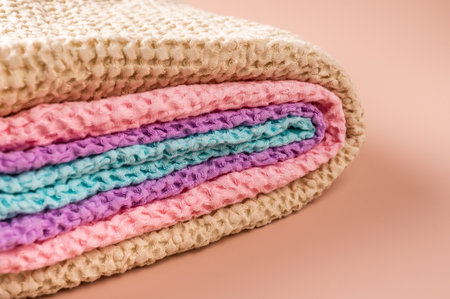 Multicolored linen and cotton bath and spa towels twisted into a roll on pink background, body care concept, close-up, copy spaceの写真素材