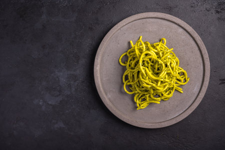 Pasta with pesto, served on gray ceramic plate on dark textured background, selective focus, top...
