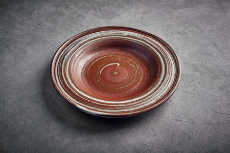 Blank ceramic brown plate on a dark background, copy space, close up