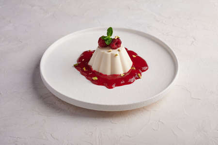 Panna cotta with raspberry syrup, pistachios, berries and mint, high key, close up