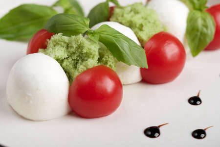 Delicious italian caprese salad with ripe tomatoes, fresh garden basil and mozzarella cheese. Macro, food style, selective focusの写真素材