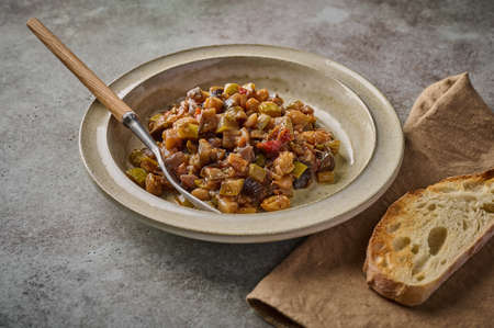 Homemade traditional Sicilian caponata with eggplant, zucchini, tomatoes, olives and ciabatta bread. Close up, copy spaceの写真素材