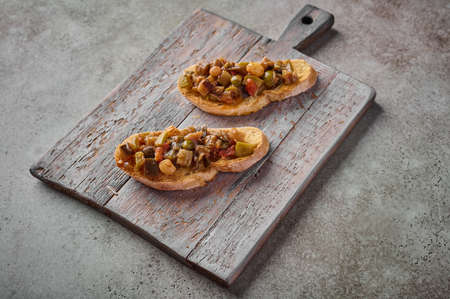 Bruschetta with homemade traditional Sicilian caponata and ciabatta bread on wooden cutting board. Close upの写真素材