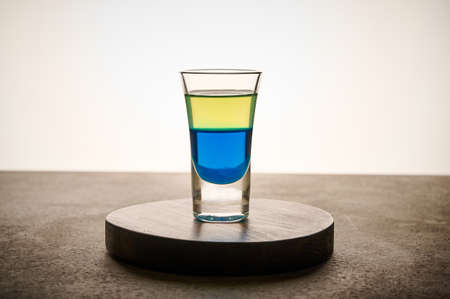 Homemade yellow and blue transparent alcohol drink in glass of limoncello and curacao, close up concept color of the Ukrainian flagの写真素材