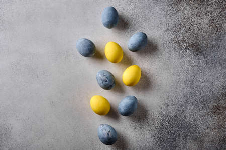 Homemade Easter colored yellow and grey marble eggs on wooden background. Top view, copy spaceの写真素材