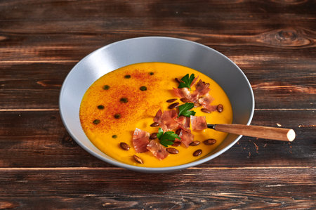 Traditional pumpkin puree cream soup with carrots, onions, ginger, garlic, coconut milk. Added seeds, fried bacon, parsley. Healthy, vegetarian food. Close upの写真素材