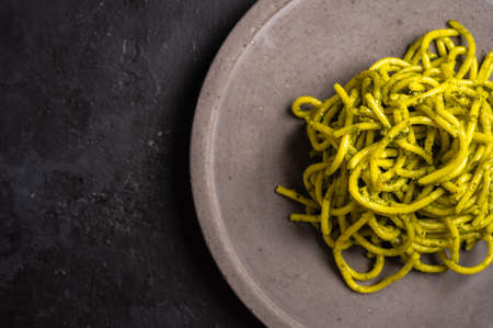 Pasta with pesto close up, served on gray ceramic plate on dark textured background, selective focus, top view, copy spaceの写真素材