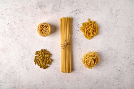 Uncooked raw bunch of spaghetti, fettuccine, girandole and tagliatelle on grey textured background. Copy space. Top viewの写真素材