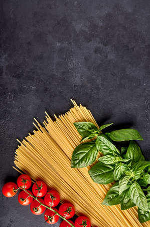 Spaghetti Italian pasta with basil leaves and tomatoes on dark textured background, arranged in the colors of the Italian flag. Vertical orientation. Copy spaceの写真素材