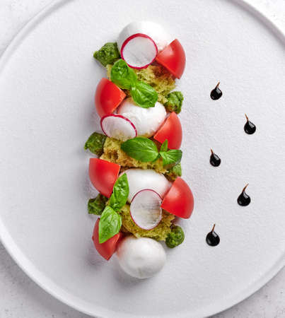 Vertical orientation delicious italian caprese salad with ripe tomatoes, fresh garden basil and mozzarella cheese. Top view, food styleの写真素材