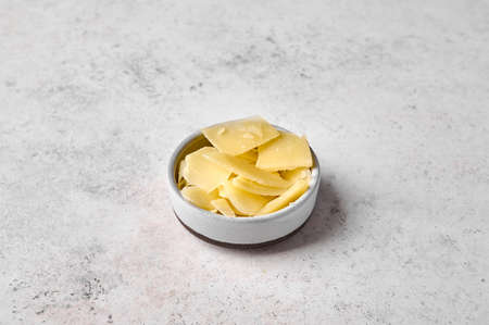 Parmesan cheese in bowl on light textured background. Close up. Copy space for text