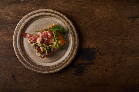 Piece of traditional Italian Roman pizza lies on rustic ceramic plate on brown wooden background, flat lay, copy spaceの写真素材