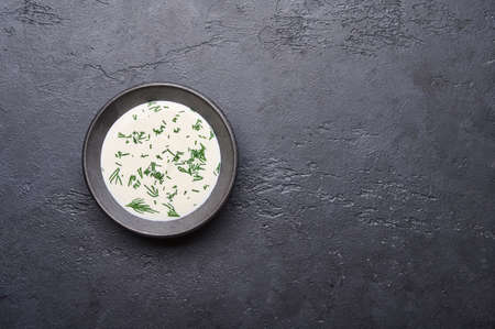 Black saucepan with sour cream and chopped greens on a dark graphite background, flat layの写真素材