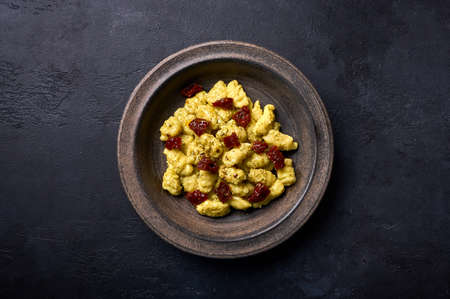 Flat lay Italian potato gnocchi with parmesan and dried tomatoes in rustic plate on a graphite dark backgroundの写真素材
