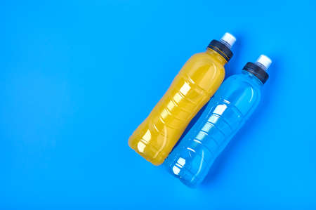 Top view isotonic energy orange yellow and blue sport drink in plastic bottles on yellow background. Allows to maintain the most optimal balance of water, salt and electrolytes when playing sportsの写真素材