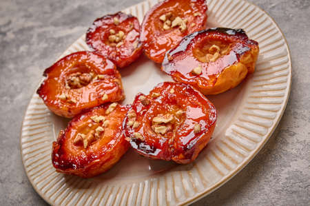 Close up baked quince with honey, walnut and cinnamon on light plate on concrete background