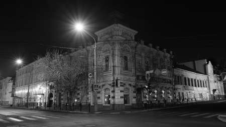 The facade of an old house at night. Street lights.