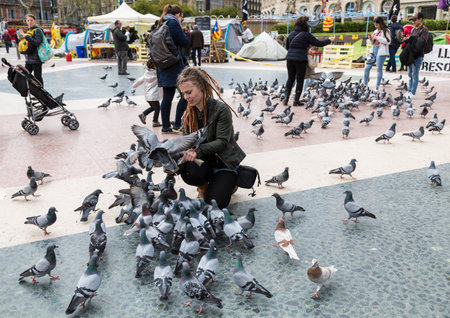 Tourists in Plaza Catalunya in Barcelona feeding the pigeons and taking pictures of them. Spainのeditorial素材