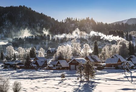 View of the winter  the village Iogach against the background of forested mountains. Altai Republic,...