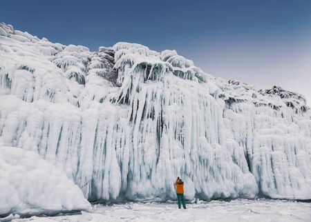 Fabulous ice icicles on the rocks of lake Baikal. Tourist photographs the icy rocks. Eastern...