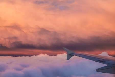 Airplane flight over the clouds at sunsetの写真素材