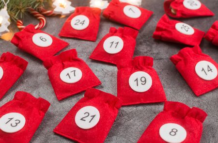 Christmas advent calendar pouches with numbers on dark background.next to the fir branches.Gifts and surprises for children.Waiting for the holiday.diy.christmas instruction.copy space.flat layの写真素材