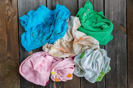 Dirty kids clothing is scattered on a wooden table.Concept of searching for information on washing...