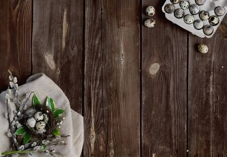 Happy Easter.Greeting card.Small eggs in a nest with willow branches on a rustic wooden...