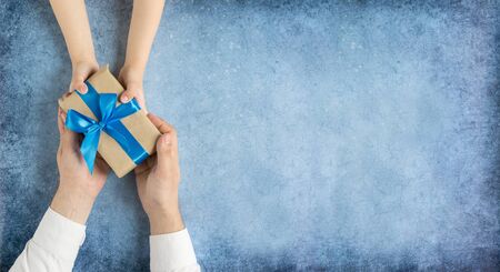 Happy fathers day.Gift in the hands of daughter and father on a blue background.I love you, dad.の写真素材
