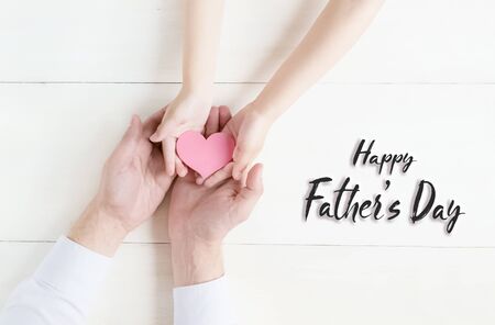 Happy fathers day.Greeting card.Gift heart in the hands of daughter and father on a white background.I love you, dad.Love and health in the familyの写真素材