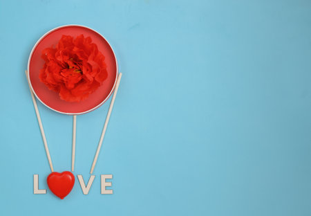 happy valentines day or mothers day greeting card with a red peony flower in a cardboard balloon and the inscription love on a blue background.Banner for your store or websiteの写真素材