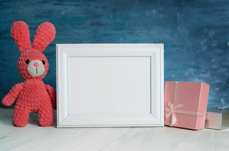Small pink bunny sits next to gifts for children and a blank white frame for childrens day and...