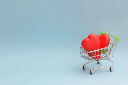 Happy Valentines Day or Mothers Day greeting card with red hearts in a shopping cart on blue...